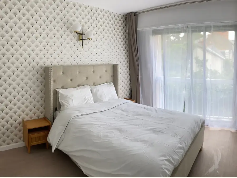 Chambre d’une résidence services, literie claire et tête de lit capitonnée.