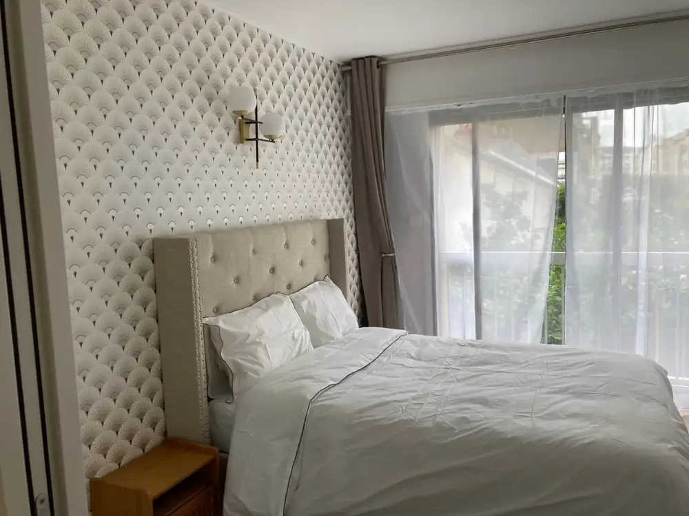 Chambre rénovée, tête de lit capitonnée.